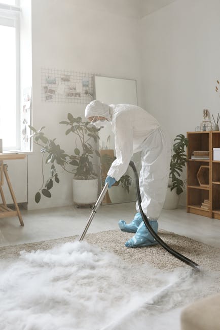 A woman with curly hair tied back, dressed in a beige jacket, blue jeans, and white sneakers, is using a yellow vacuum cleaner to carry out surface cleaning on a large, ornate area rug with intricate 